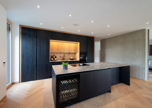 Moderne Küche mit dunklen Schränken, Kochinsel mit Marmorplatte und integriertem Weinkühlschrank