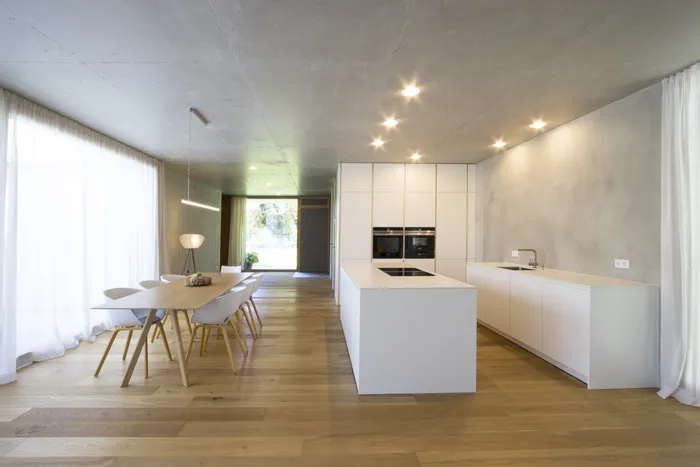 Moderne offene Küche mit weißer Kücheninsel, Esstisch und Holzfußboden