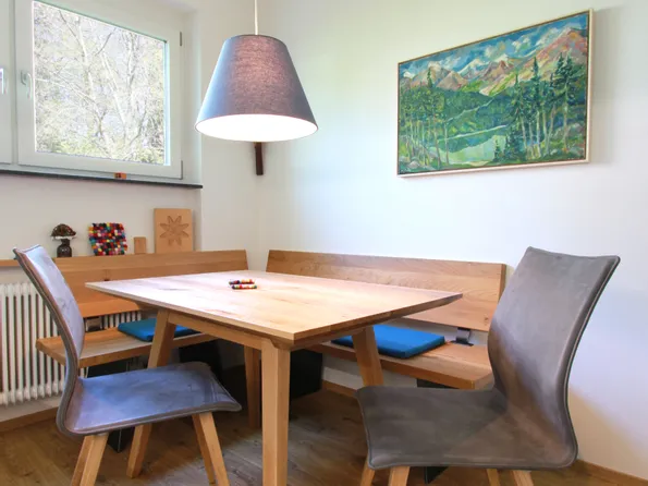 Moderne Essecke mit Holztisch, grauen Stühlen und Landschaftsbild an der Wand