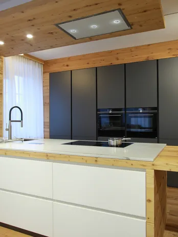 Moderne Küche mit Holzverkleidung, Kochinsel, schwarzem Backofen und Induktionskochfeld