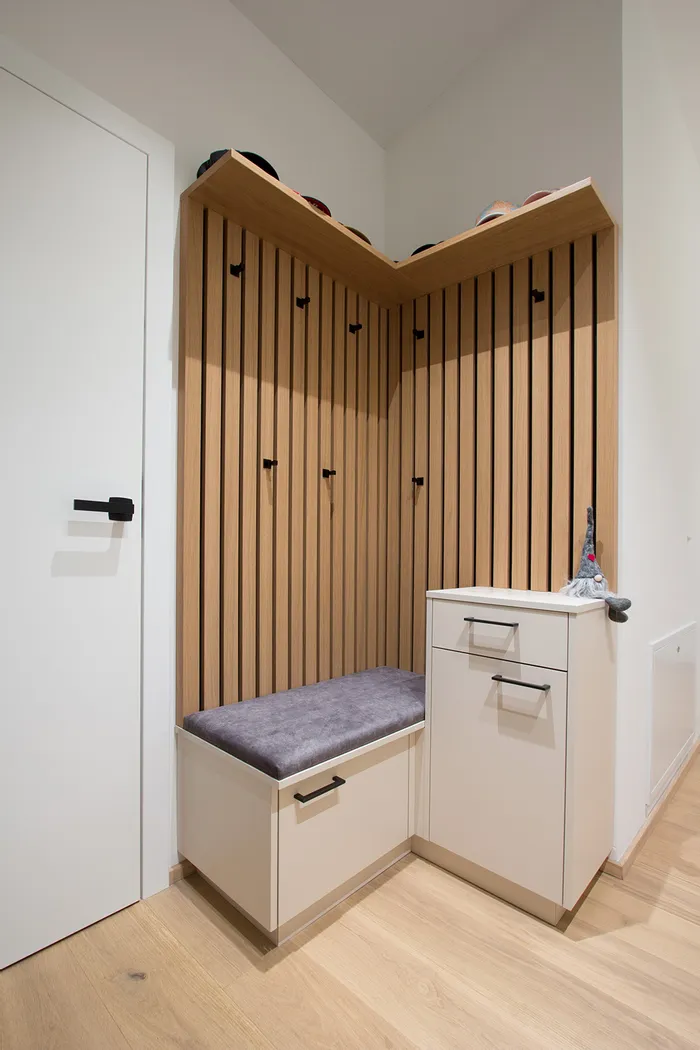 Moderner Garderobenbereich mit Sitzbank, Holzwand mit Haken und Stauraum in heller Diele