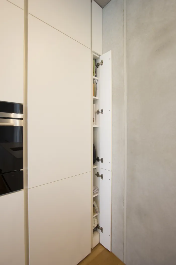 Schmaler Einbauschrank mit offener Tür und Regalen für Bücher und Haushaltsgegenstände