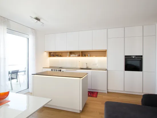 Moderne weiße Einbauküche mit Kochinsel und Holzfußboden