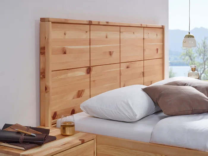Holzbett mit hoher Kopfstütze aus massivem Holz in modernem Schlafzimmer mit Bergblick