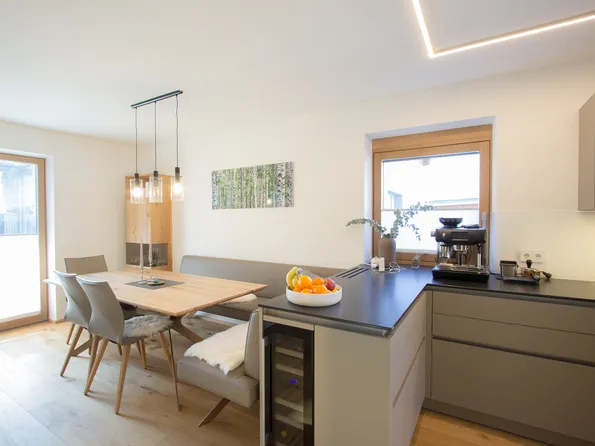 Moderne Wohnküche mit Esstisch, Hängelampen, Obstschale und Espressomaschine am Fenster