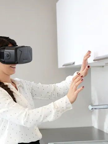 Frau mit Oculus VR-Headset interagiert in virtueller Realität in moderner Küche