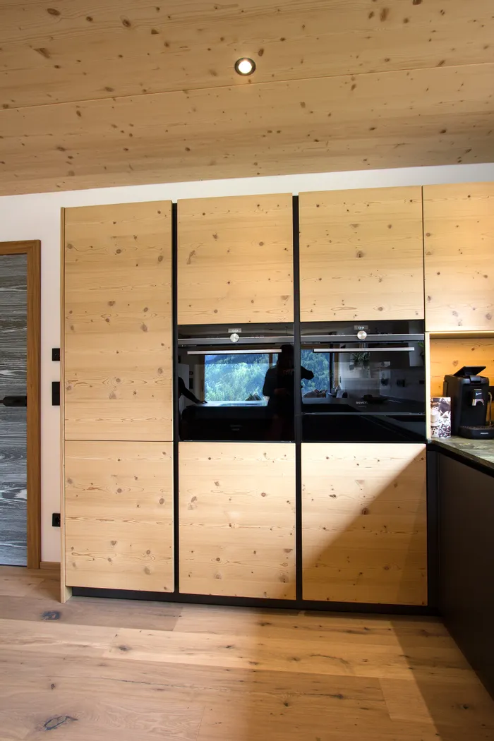 Moderne Einbauküche mit hellen Holzfronten und schwarzen Einbaugeräten