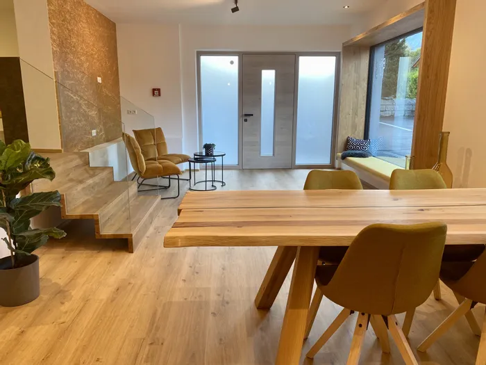 Modernes Wohnzimmer mit Holztreppe, Esstisch und großen Fenstern mit Sitzbank