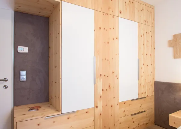 Einbauschrank aus hellem Holz mit weißen Türen in einem modernen Schlafzimmer