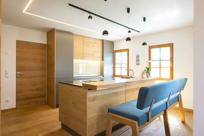 Moderne Küche mit Holzfronten, Kochinsel, Hängelampen und blauer Sitzbank