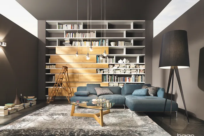 Modernes Wohnzimmer mit blauer Eckcouch, großer Bücherwand und Stehleiter