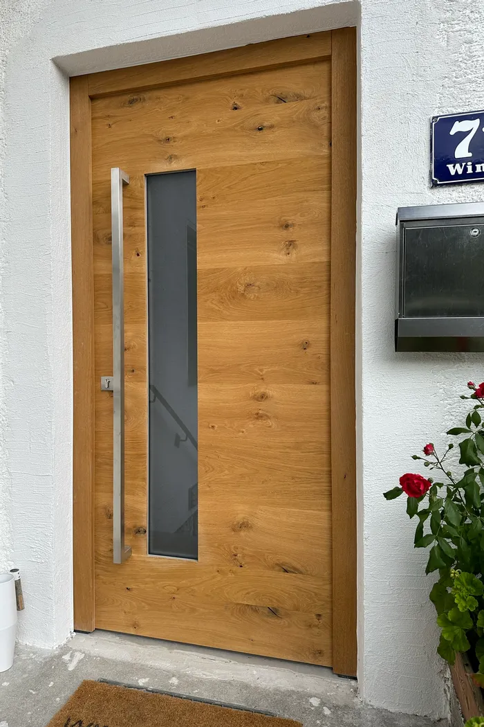 Moderne Eingangstür aus Holz mit vertikalem Glasfenster und Edelstahlgriff