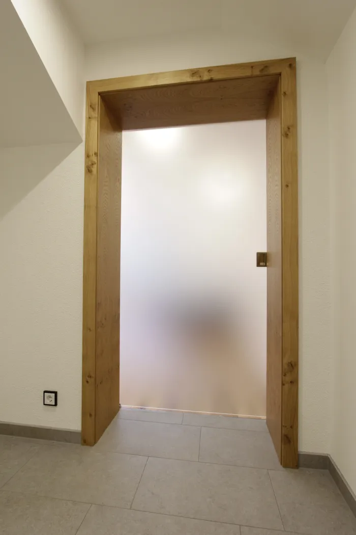 Geöffnete Tür mit Holzrahmen und satiniertem Glas in modernem Innenraum