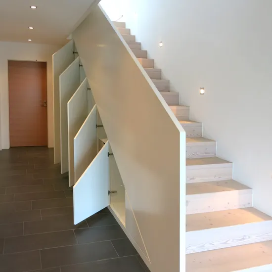 Moderne Holztreppe mit integrierten Staufächern unter jeder Stufe in einem minimalistischen Flur