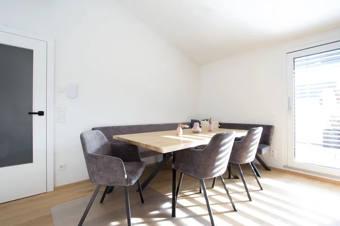 Heller Essbereich mit Holzstuhl, Eckbank, grauen Stühlen und Deko auf Holztisch