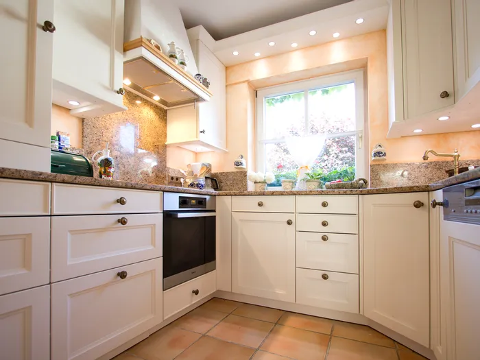 Helle Landhausküche mit weißen Schränken, Granit-Arbeitsflächen und großem Fenster mit Tageslicht