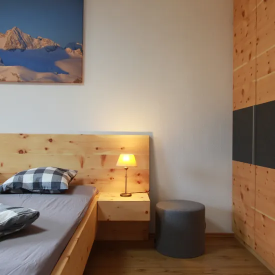 Modernes Schlafzimmer mit Holzbett, Nachttischlampe und Einbauschrank aus Holz