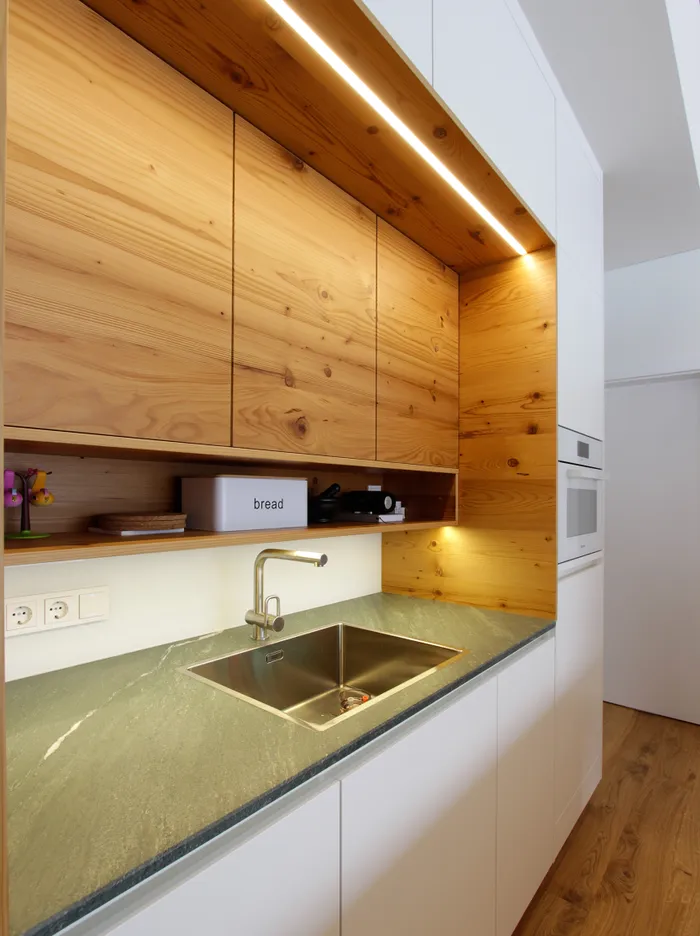 Moderne Küche mit Spüle, Holzoberschränken, LED-Leiste und weißem Brotbehälter