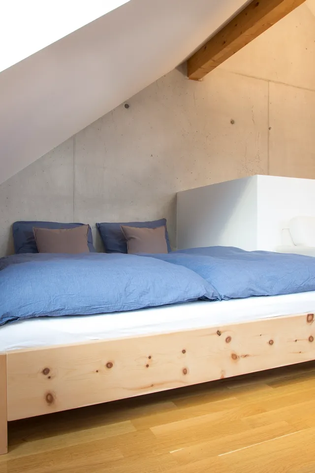Modernes Schlafzimmer im Dachgeschoss mit Holzboden, Doppelbett und blauer Bettwäsche