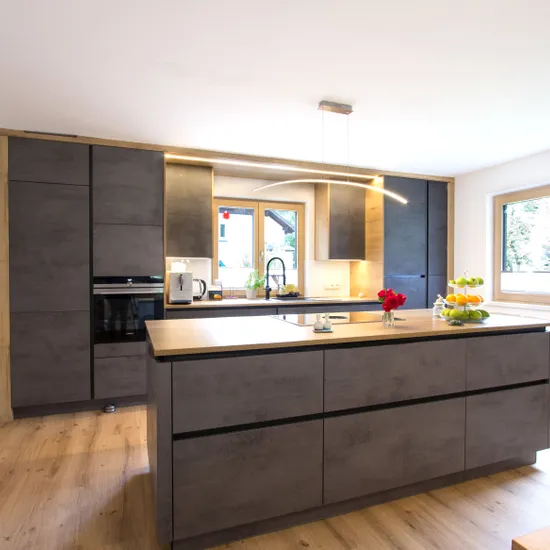 Moderne Einbauküche mit Kochinsel, grauen Fronten und Holzdetails bei Tageslicht