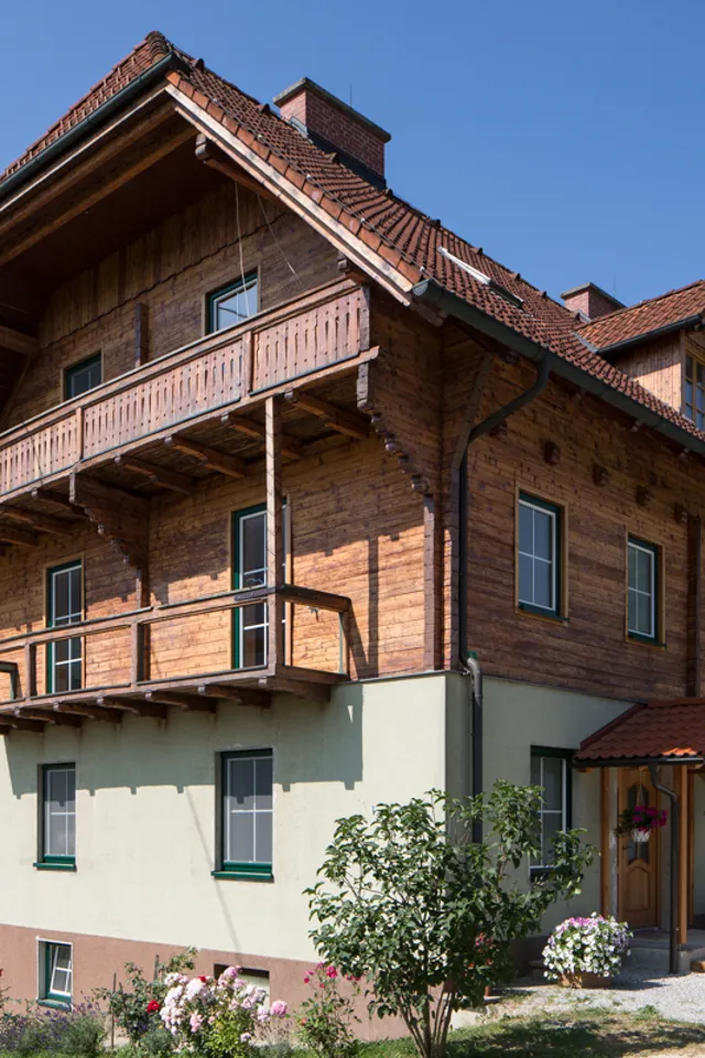 Traditionelles österreichisches Landhaus mit Holzfassade und Balkon in bergiger Landschaft