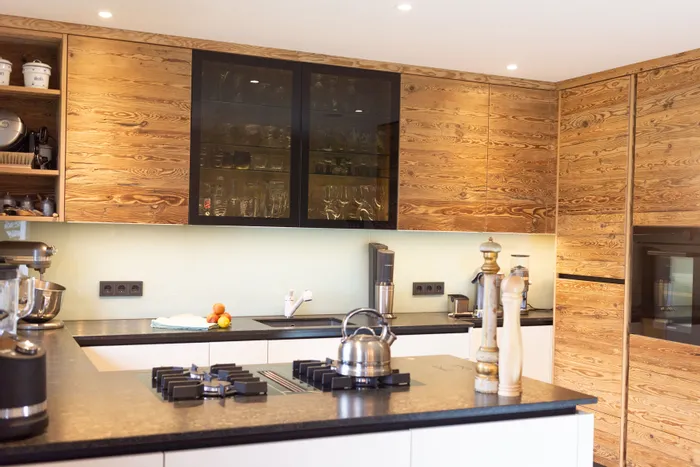 Moderne Küche mit Holzfronten, schwarzer Arbeitsplatte und Edelstahlgeräten