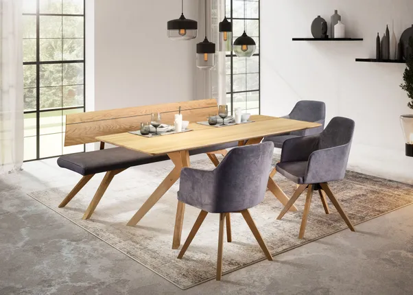 Modernes Esszimmer mit Holztisch, grauen Polsterstühlen und Bank auf Teppich vor großen Fenstern