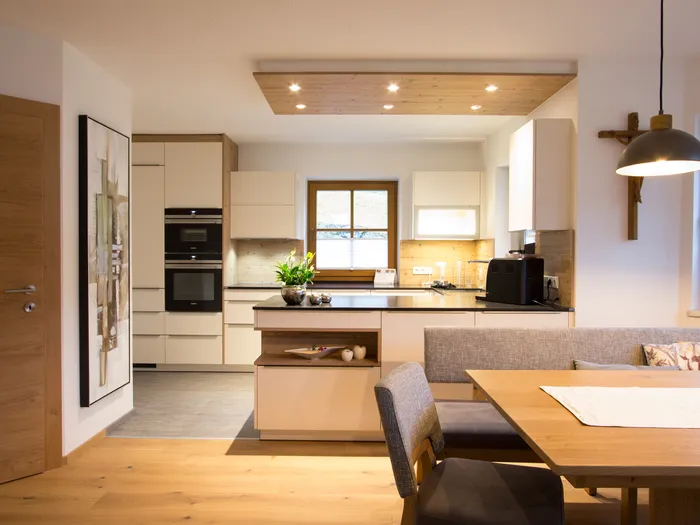 Moderne Einbauküche mit Holzdetails, Essbereich und natürlichem Licht durch Fenster