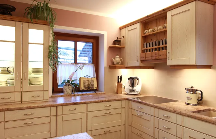 Moderne Landhausküche mit hellen Holzmöbeln, Arbeitsplatten aus Stein und Küchenmaschinen