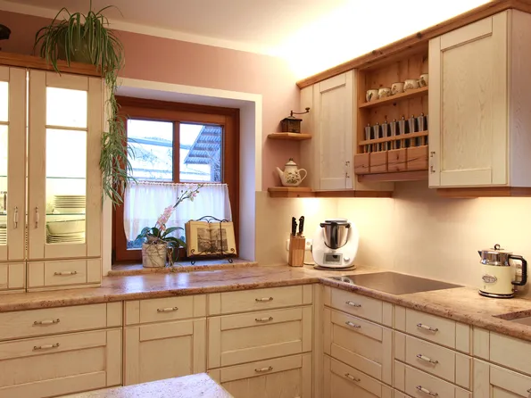 Moderne Landhausküche mit hellen Holzmöbeln, Arbeitsplatten aus Stein und Küchenmaschinen