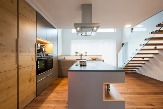 Moderne offene Küche mit Kochinsel, Holzfußboden und freitragender Treppe