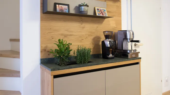 Moderne Kaffeestation mit Espressomaschine, Kräutern und Wandregalen mit Fotos und Dekoration