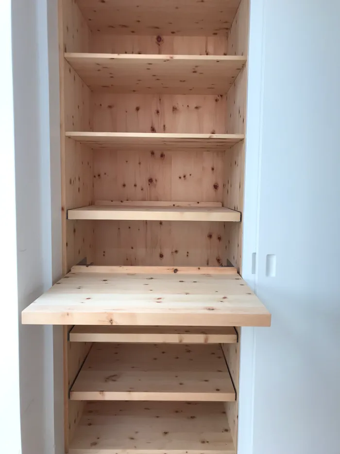 Offener Holzschrank mit mehreren Einlegeböden und ausziehbarer Ablage