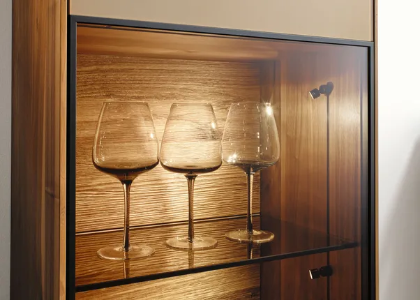 Drei Weingläser in einem beleuchteten Holzvitrinenschrank auf Glasboden
