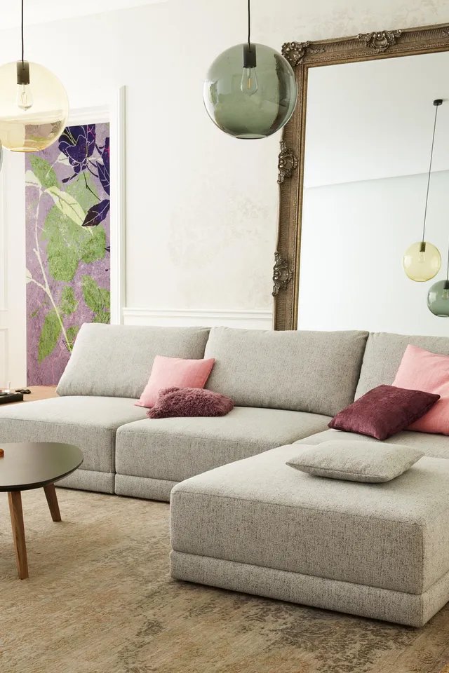 Modernes Wohnzimmer mit grauem Ecksofa, bunten Kissen und großem Spiegel an der Wand