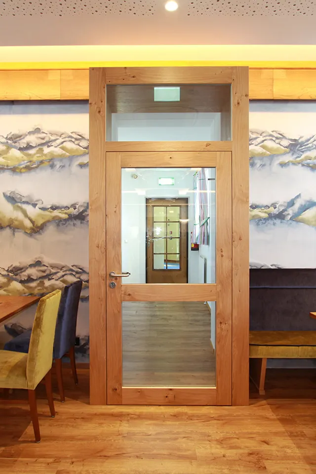 Gemütlicher Restaurantbereich mit Holzmöbeln und Wandbild in Berglandschaft-Optik