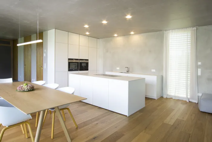 Moderne offene Küche mit weißer Kücheninsel, Holzboden und Essbereich mit Holztisch