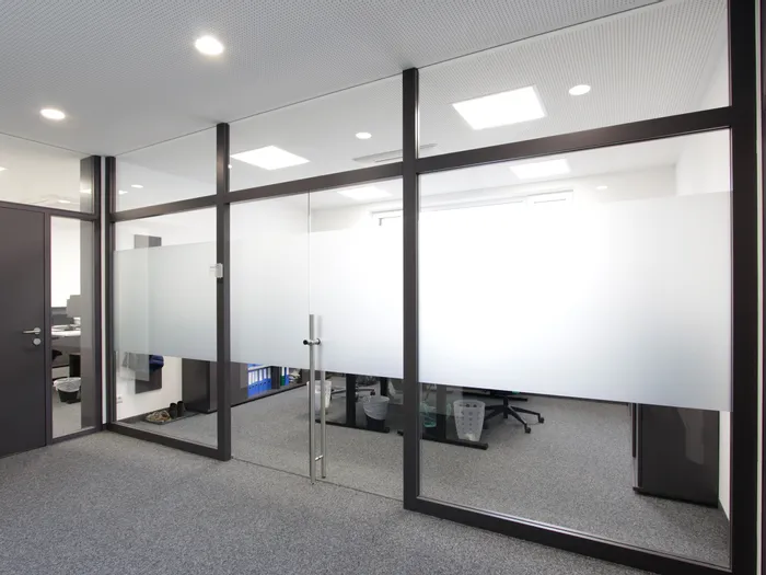 Modernes Büro mit Glastrennwand und grauem Teppichboden