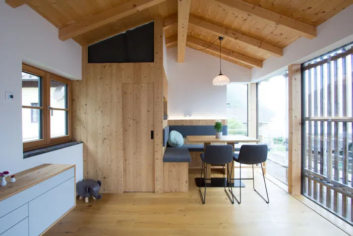 Modernes Esszimmer mit Holzdecke, großen Fenstern und gemütlicher Sitzecke im skandinavischen Stil