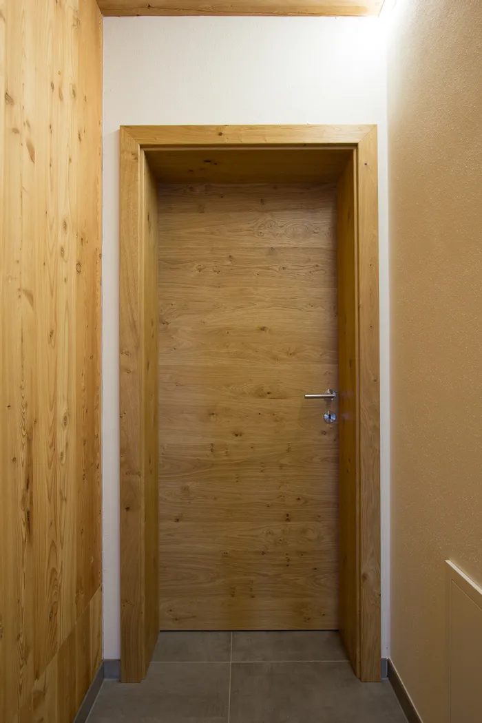 Geschlossene Innentür aus hellem Holz in einem modernen Flur mit Holzwandverkleidung