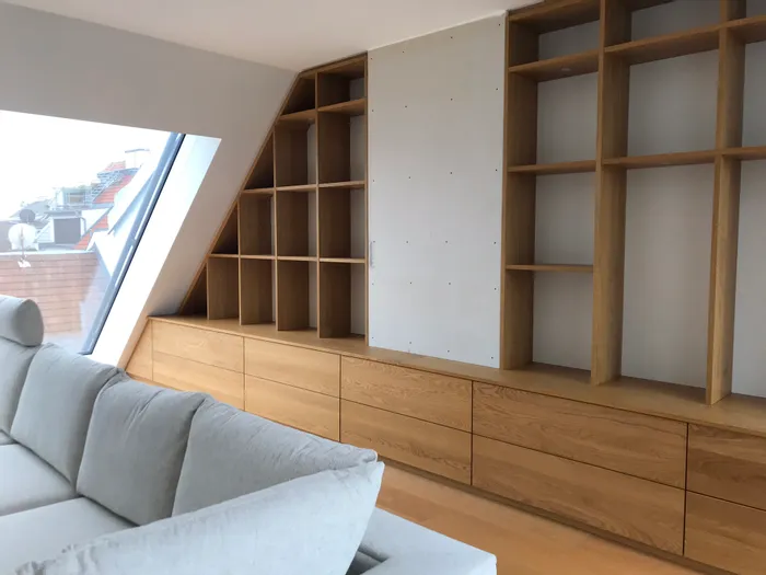 Modernes Wohnzimmer mit eingebautem Holzregal unter Dachschräge und großem Fenster