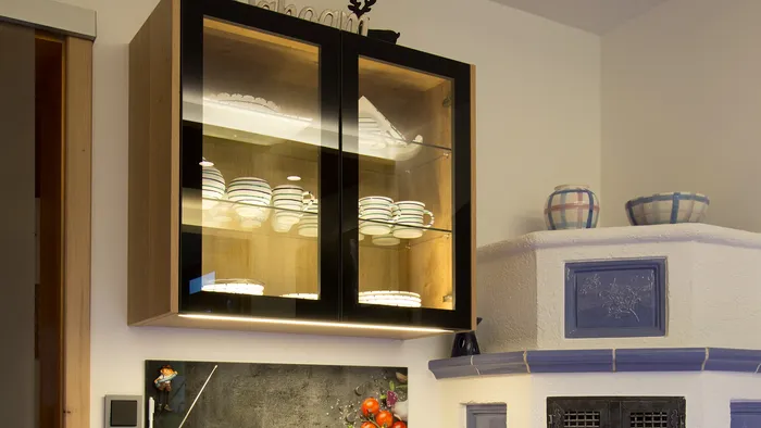 Moderne Küchenzeile mit Holzschränken, Glasvitrine, Radio und Obstkorb auf schwarzer Arbeitsplatte