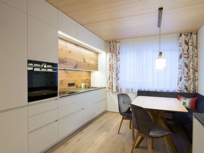 Moderne Einbauküche mit Holzdekor, schwarzem Herd und gemütlicher Sitzecke am Fenster