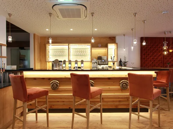 Moderne Hotelbar mit Holztheke, Barhockern und stilvoller Beleuchtung