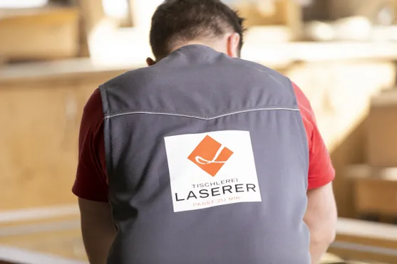 Rückansicht eines Tischlers mit Logo der Tischlerei Laserer auf seiner Arbeitskleidung