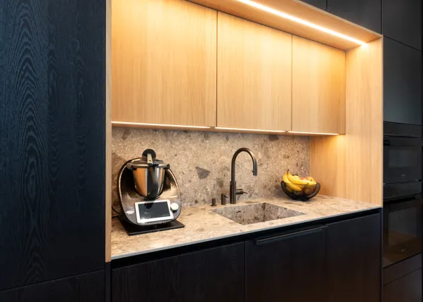 Moderne Einbauküche mit dunklen Schränken, Naturstein-Arbeitsplatte und Küchenmaschine