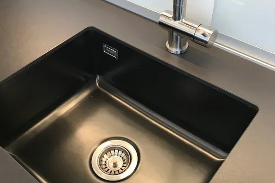 Moderne schwarze Spüle mit Edelstahlarmatur in einer minimalistischen Küche