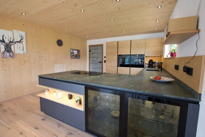 Moderne Küche mit Holzverkleidung, Kochinsel aus Stein und eingebauten Elektrogeräten