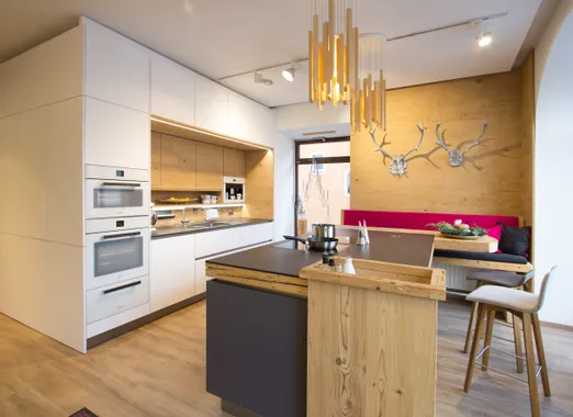 Moderne Einbauküche mit Holzverkleidung, Kochinsel und gemütlicher Sitzecke mit Hirschgeweih-Deko