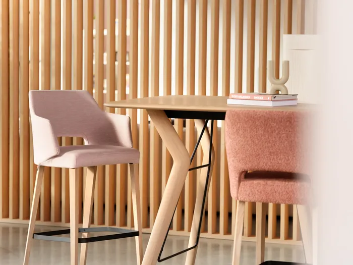 Moderne Holzstühle mit rosa Polsterung an rundem Tisch vor Holzlattenwand